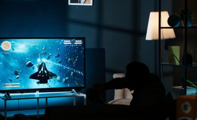 Guy feeling lucky playing online gaming tournament on smart tv Guy feeling lucky playing online gaming tournament and winning the round, plugging his console into television and having fun with successful competition at night. First person shooter. Camera B.